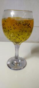 A glass cup filled with golden saffron and small syrup seeds on a bright kitchen counter symbolizes unique hydration for health and weight loss.