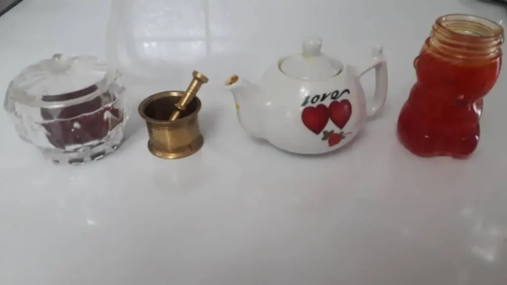 Liquid saffron in a glass jar, premium saffron threads in a clear container, a small porcelain teapot, and a brass mortar for grinding saffron