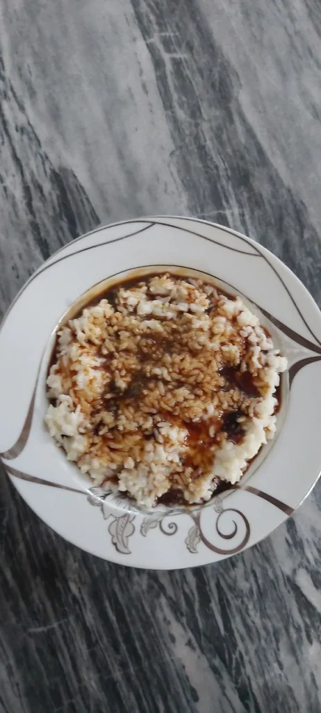 A white porcelain dish filled with rice milk and drizzled with date syrup on top.