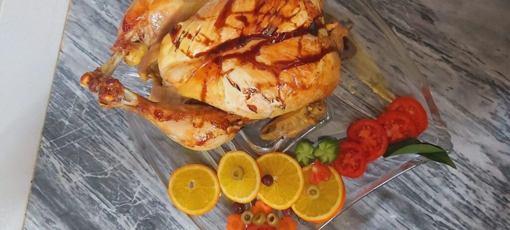 Chicken biryani in crystal dish with pomegranate sauce and vegetable garnish.