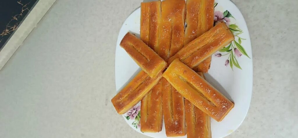 Golden Shirini Zaban pastries on a white plate.