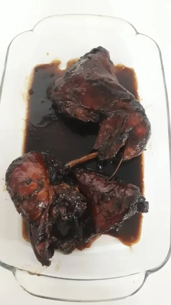 Pyrex dish filled with chicken thighs and breasts topped with pomegranate molasses sauce.