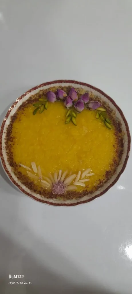 Sholeh Zard dessert in a rectangular Pyrex dish, adorned with cinnamon powder, rosebuds, and pistachio slivers.