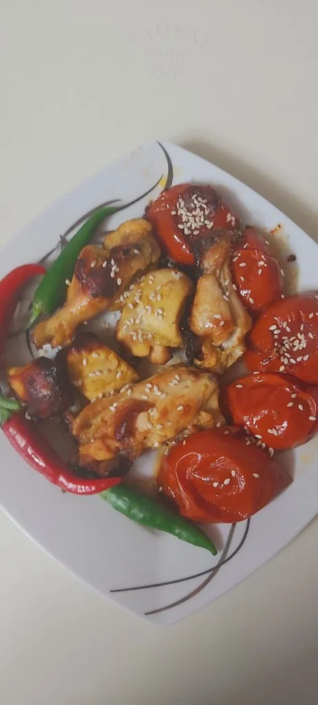 Close-up of grilled chicken kebabs topped with sesame seeds, served with roasted tomato and pepper
