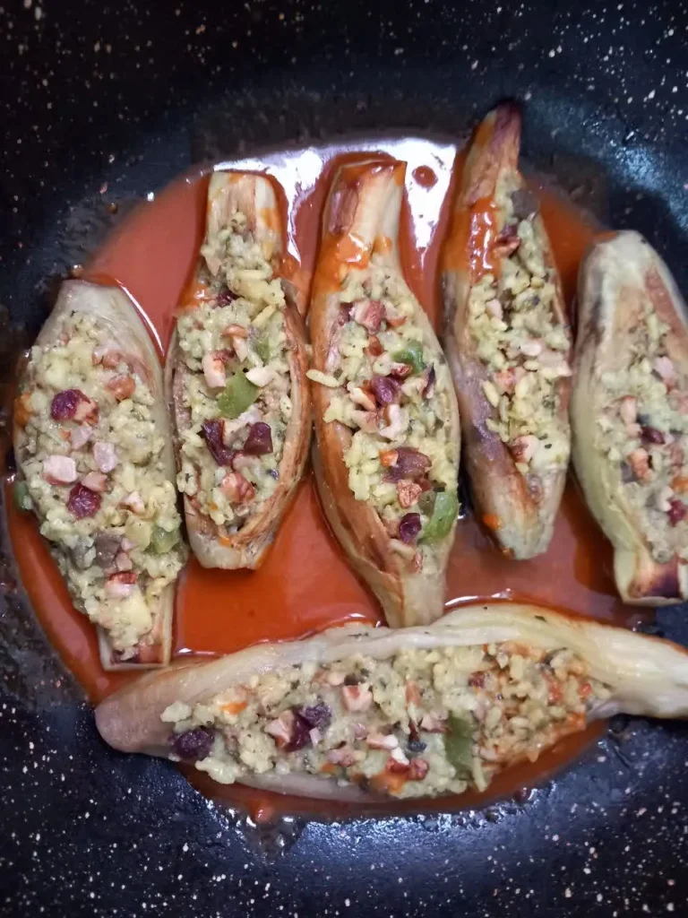 Stuffed peeled eggplant with rice, diced bell pepper, sausage, and tomato, served in a savory tomato paste sauce.
