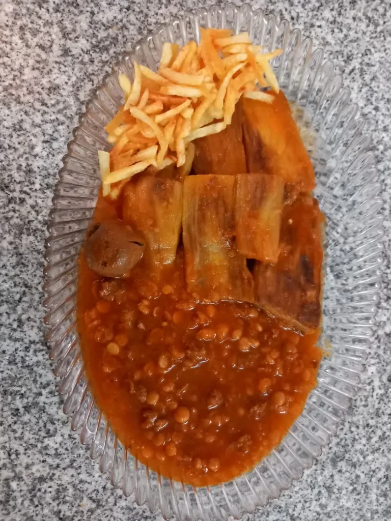 A Pyrex dish with fried eggplants and golden potato sticks on one side, and Persian Gheimeh Bademjan stew with split peas and meat on the other side.