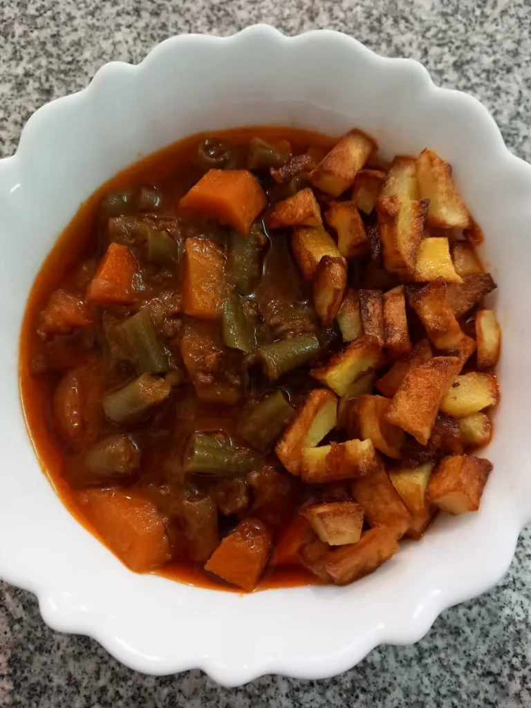 Hearty green bean stew with meat, green beans, and a side of crispy fried potatoes.
