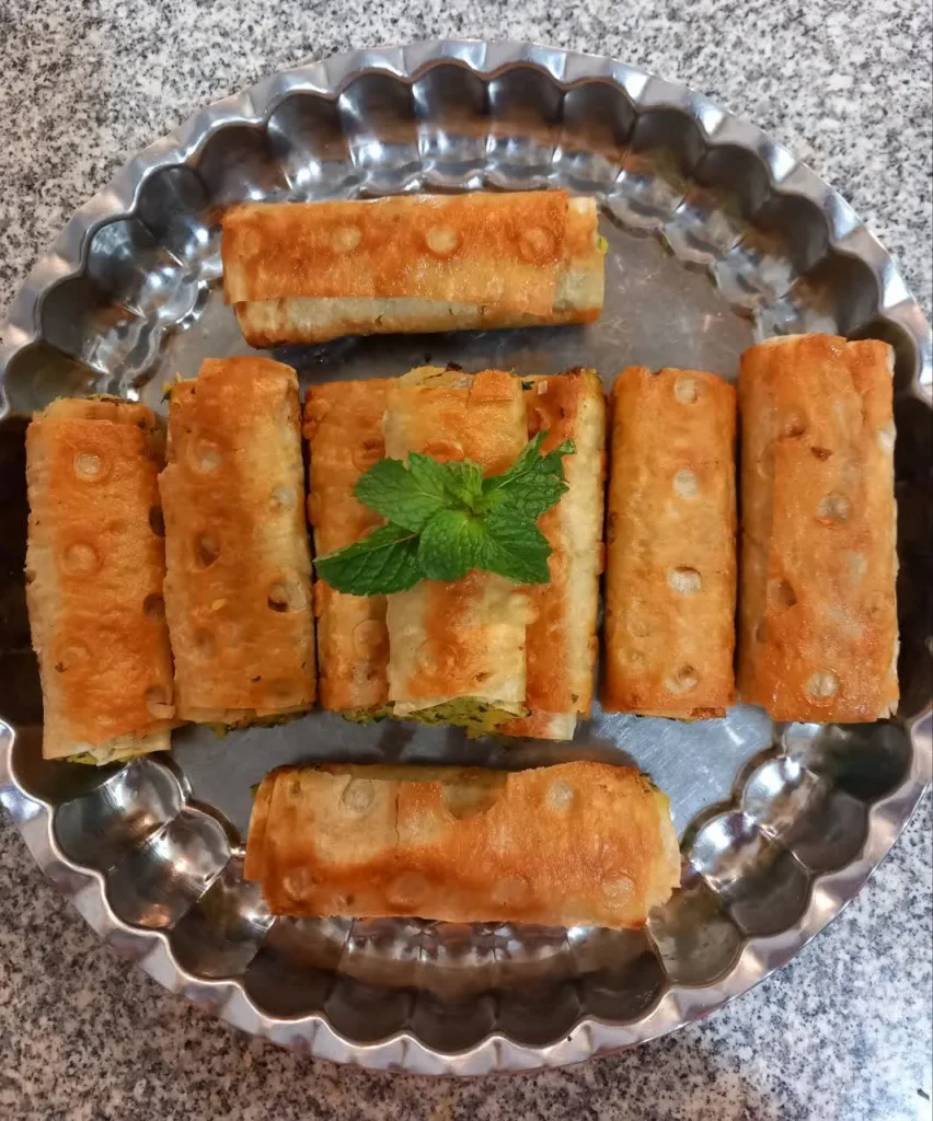 Golden-brown potato and vegetable samosas, rolled in bread and garnished with fresh mint leaves.