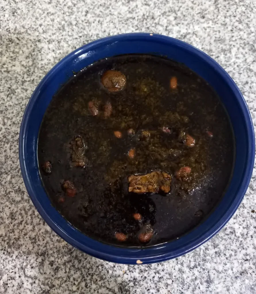 Close-up of Persian Ghormeh Sabzi (herb stew) in a blue ceramic bowl.