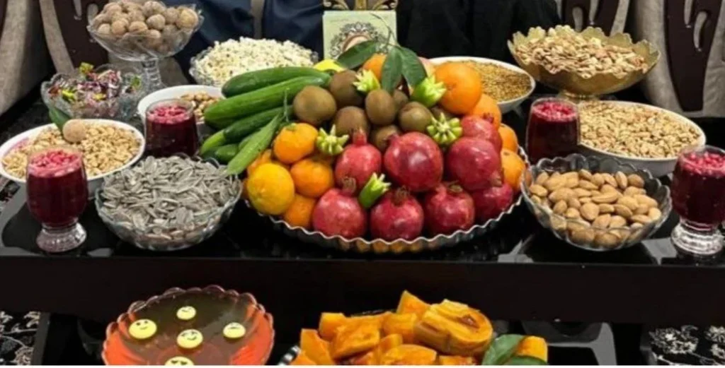 Traditional Yalda Night table with red gelatin, pumpkin, pomegranate, mixed nuts, popcorn, wheat and hemp seed snack, and fresh fruits arranged in a round platter